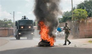A Burundian army soldier pours water on a burning-tyre roadblock erected by opposition protesters in the capital Bujumbura, Burundi Monday, April 27, 2015. Street protests continued Monday in Burundi as anger mounts over the ruling party's decision on Saturday to nominate President Pierre Nkurunziza for a third term. (AP Photo/Eloge Willy Kaneza)