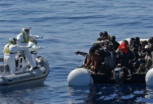 In this photo made available Thursday, April 23, 2015, an Italian Financial Police rescue unit approaches an inflatable dinghy crowded with migrants off the Libyan coast, in the Mediterranean Sea, Wednesday, April 22, 2015.  European Union leaders gathering for an extraordinary summit are facing calls from all sides to take emergency action to save lives in the Mediterranean, where hundreds of migrants are missing and feared drowned in recent days. (Alessandro Di Meo/ANSA via AP Photo) ITALY OUT