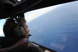 In this April 13, 2014 photo taken from the Royal New Zealand air force (RNZAF) P-3K2-Orion aircraft, co-pilot Squadron Leader Brett McKenzie looks out of a window while searching for debris from missing Malaysia Airlines Flight 370, in the Indian Ocean off the coast of western Australia. The search area for the missing flight will be expanded by another 60,000 square kilometers (23,000 square miles) in the Indian Ocean if the jetliner is not found by May, officials said Thursday, April 16, 2015. Malaysian Transport Minister Liow Tiong Lai told reporters that Malaysia, Australia and China, which are leading the hunt for the Boeing 777 that went missing on March 8 last year, are "committed to the search." (Greg Wood/Pool Photo via AP)
