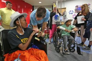 Former Colts player Dallas Clark, center, meets AJ Carter-Harris, 13, from Indianapolis, at Riley Hospital for Children, Tuesday, April 7, 2015, in Indianapolis. Country music star Garth Brooks and other celebrities attended the Child Life Zone ribbon cutting at the hospital Tuesday, which was funded through the Teammates for Kids foundation, which Brooks co-founded in 1999. (AP Photo/The Indianapolis Star, Kelly Wilkinson)  NO SALES