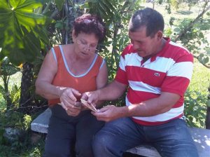 CORRECTS BYLINE TO MILEXSY NOT MILEXY - In this Friday, March 20, 2015 photo, Fidelia Rodriguez and her son Camilo hold old photos of U.S. citizen Daniel Smith and his family from before the Cuban Revolution in the Isle of Pines, Cuba. Fidelia's father worked as a gardener for the Smiths before the family's property was confiscated by the new government. (AP Photo/Milexsy Duran)