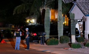 Phoenix Police Department officers stand out in front of a home where authorities say five people were killed inside after a shooting Thursday, April 16, 2015, in Phoenix. The names and ages of the three men and two women weren't immediately released, but police said they all were adults. (AP Photo/Ross D. Franklin)