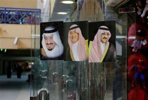 FILE - In this April 16, 2015 file photo, images of Saudi King Salman, left, then Crown Prince Muqrin, center, and then Deputy Crown Prince Mohammed bin Nayef are displayed on a shop door at the al Aqeeliya market in Riyadh, Saudi Arabia. Saudi Arabia's King Salman on Wednesday removed his half-brother from the post of crown prince and named his nephew, the country's Interior Minister, in his place. The post of crown prince secures Prince Mohammed bin Nayef as the most likely successor to King Salman. (AP Photo/Hasan Jamali, File)