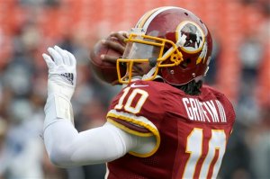 In this photo taken Dec. 28, 2014, Washington Redskins quarterback Robert Griffin III (10) warms up before an NFL football game against the Dallas Cowboys in Landover, Md. Griffin fifth-year contract option for the 2016 season will be exercised by the Washington Redskins. New general manager Scot McCloughan says the team will submit the proper paperwork to the NFL by next week's deadline. (AP Photo/Alex Brandon)