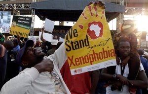 A man holds a poster reading "we stand against xenophobia"  during a march in Johannesburg, South Africa, Thursday, April 23, 2015, protesting against recent attacks on immigrants that killed seven people. The protesters walked through the center of Johannesburg passing neighborhoods that are home to many immigrants, a large number of whom come from other African countries. ( AP Photo/Themba Hadebe )