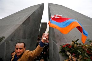 A man waves Armenian and Georgian flags at a memorial to Armenians killed by the Ottoman Turks, during marking the centenary of the mass killings, in Yerevan, Armenia, Friday, April 24, 2015. Armenians on Friday mark the centenary of what historians estimate to be the slaughter of up to 1.5 million Armenians by Ottoman Turks, an event widely viewed by scholars as genocide. Turkey, however, denies the deaths constituted genocide and says the death toll has been inflated. (AP Photo/Sergei Grits)