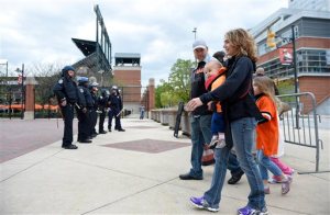 Baseball fans make their way towards Oriole Park at Camden Yards as Baltimore police stand watch, Monday, April 27, 2015, in Baltimore. The baseball game between the Baltimore Orioles and the Chicago White Sox is postponed. (AP Photo/Nick Wass)