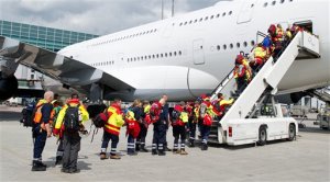 Members of a German rescue organization board a plane at the airport in Frankfurt, central Germany, Sunday, April 26, 2015, for their flight to earthquake-torn Nepal. International Search and Rescue Germany says a team of 52 relief workers including doctors, experts trained in searching for people buried under rubble and several dog squads will fly to Nepal. (Christoph Schmidt/dpa via AP)