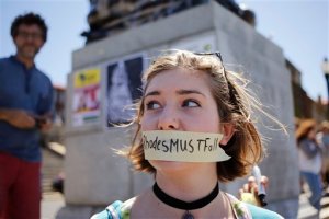 In this photo taken on Friday, March 20, 2015, a student at the Cape Town university takes part in a protest against a statue of British colonialist Cecil John Rhodes, rear,  on display on the university campus near the city of Cape Town, South Africa.   On March 9, 2015, a South African student protester tossed faeces onto the statue of British colonialist Cecil John Rhodes at the University of Cape Town, igniting nationwide calls to remove other statues of former white leaders, and the uproar continues as part of a larger discourse about change in South Africa, and the legacy of apartheid. (AP Photo/Schalk van Zuydam)