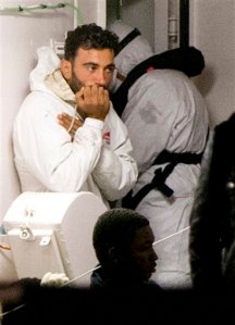 Mohammed Ali Malek, one of the survivors of the boat that overturned off the coast of Libya on Saturday, waits to disembark from Italian Coast Guard ship Bruno Gregoretti, at Catania Harbor, Italy, Monday, April 20, 2015. Mohammed Ali Malek and Mahmud Bikhit were taken in custody by Italian Police on suspicion of being crew members aboard a smuggler's boat crammed with hundreds of people that overturned off Libya's coast as rescuers approached, causing what could be the Mediterranean's deadliest known migrant tragedy and intensifying pressure on the European Union Sunday to finally meet demands for decisive action. (AP Photo/Alessandra Tarantino)