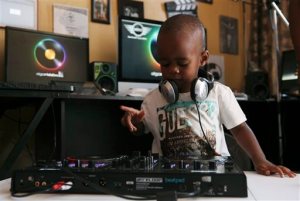 In this Monday, April 6, 2015 photo, two-year-old Oratilwe Hlongwane, also known as DJ AJ to his fans, plays with the buttons and knobs of a sophisticated music system in control of the beat of the bass-heavy house music at his Alexandra home in Johannesburg. The toddler is already able to select and play music from a laptop and has become a viral phenomenon on South Africa's social media.