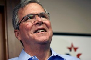 In this April 17, 2015, photo, former Florida Gov. Jeb Bush smiles while speaking to reporters after a "Politics and Eggs" event, a breakfast fixture for 2016 presidential prospects at Saint Anselm College in Manchester, N.H. Bush is preparing to embark on an experiment in presidential politics: delegating many of the nuts-and-bolts tasks of seeking the White House to a separate political organization that can raise unlimited amounts of campaign cash. (AP Photo/Elise Amendola)