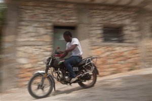 In this May 17, 2015 photo, Joseph Marc Carel, motorcycle taxi driver travels from his home to pick up clients in Port-au-Prince, Haiti. Carel would like to find a job thats safer than driving a two-wheeled taxi in Port-au-Prince.  He says he has nightmares that his job may cost him another limb. (AP Photo/Dieu Nalio Chery)