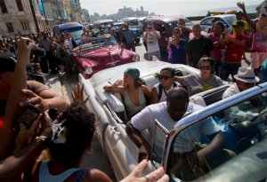 Fans take photographs of pop artist Rihanna, wearing a green scarf, as she is transported in an American classic car, after a photo shoot with photographer Annie Leibovitz at a building on the Malecon, in Havana, Cuba, Friday, May 29, 2015. (AP Photo/Desmond Boylan)