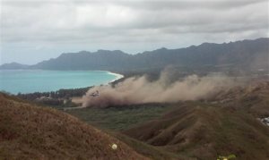 Debris rises as a Marine Corps Osprey aircraft, not pictured, makes a hard landing on Bellows Air Force Station near Waimanalo, Hawaii, Sunday, May 17, 2015. Several Marines from the aircraft were taken to a hospital, military officials say. (AP Photo/Kimberly Hynd)