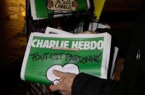 FILE - In this Wednesday, Jan. 14, 2015, file photo, a seller of newspapers stocks several Charlie Hebdo newspapers at a newsstand in Nice, France. Under armed security and a cloud of conflicted opinions and emotions, the French satirical magazine Charlie Hebdo was presented a freedom of expression award on Tuesday, May 5, 2015, in New York, from the PEN American Center. In accepting the award, Editor-in-Chief Gerard Biard noted the magazine's history of shocking readers with its irreverent drawings of religious figures. (AP Photo/ Lionel Cironneau, File)