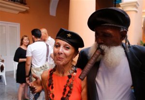 In this May 20 2015 photo, Patricia Farber, wife of US art collector Howard Farber, stands with well known Cuban street entertainer Hermenegildo Arencibia, at a cultural event organized by the Farber Foundation in Havana, Cuba. The thaw in relations between the U.S. and Cuba has led to a dramatic 36 percent increase in visits by Americans to Cuba since January compared to the same period last year, along with a 14 percent rise in arrivals from around the world. (AP Photo/Desmond Boylan)