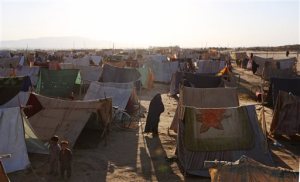 In this Thursday, May 21, 2015 photo, an Afghan refugee woman walks near her tent in a makeshift camp on the outskirts of Kunduz province, north of Kabul, Afghanistan. When the Taliban descended a month ago on Dam Shakh, a hamlet on the wheat-growing plains of northern Afghanistans Kunduz province, nobody was prepared. By the time they were beaten back from the provincial capital of Kunduz, more than 100,000 people were forced from their homes and total of 204 war-wounded were admitted to Kunduzs only trauma hospital, run by French NGO Medecins Sans Frontieres in less than a month. (AP Photo/Rahmat Gul)