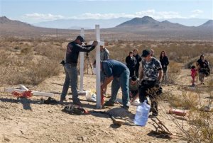 FILE - In this Nov. 20, 2013, file photo, residents of Victorville, Calif., and surrounding communities place crosses near the graves where the McStay family was found in Victorville, Calif. Prosecutors are expected to reveal Tuesday, May 19, 2015, the evidence that led them to Charles "Chase" Merritt,  the sole suspect in the case, at a preliminary hearing. A judge previously denied a media request to unseal investigative filings and authorities have said little about the murders of Joseph McStay, 40, his wife, Summer, 43, and their sons, 4-year-old Gianni and 3-year-old Joseph Jr. (James Quigg/The Victor Valley Daily Press via AP, File)