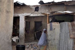 A girl walks past a house damaged in Saturday's rocket propelled grenades by Islamic extremist in Maiduguri, Nigeria, Sunday, May 31, 2015. A bomb injured four people in a market Sunday in Maiduguri, a day after the northeastern Nigerian city was hit by a suicide bomber who killed 16 in a mosque. (AP Photo/Jossy Ola)