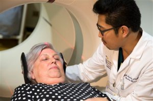 In this photo taken May 19, 2015, Judith Chase Gilbert, of Arlington, Va., is loaded into a PET scanner by Nuclear Medicine Technologist J.R. Aguilar at Georgetown University Hospital in Washington. Gilbert shows no signs of memory problems but volunteered for a new kind of scan as part of a study peeking into healthy brains to check for clues about Alzheimer's disease.  (AP Photo/Evan Vucci)