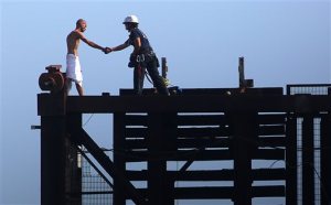 A member of the Fort Lauderdale Fire Rescue Tactical Rescue Team rescues a naked man on top of a raised drawbridge on Friday, May 22, 2015 in Fort Lauderdale, Fla.   Witnesses said the unidentified man was swimming in the river earlier and was walking across the railroad bridge Friday morning when it began to rise, forcing him to scamper to the top.   (Michael Clary/South Florida Sun-Sentinel via AP)  MAGS OUT
