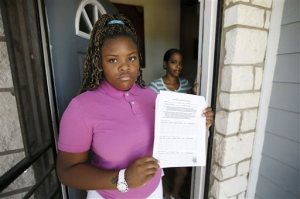 Natod'Ja Washington, front, 16, poses for a photo with her mother Natasha Holloway at their home as Washington holds a student sign in sheet for truancy court Friday, June 19, 2015, in Dallas. The form must be signed by all of her teachers confirming Washington's attendance in school. (AP Photo/Tony Gutierrez)