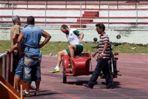 New York Cosmos player Adam Moffat tries out the sidecar of an old Russian motorcycle, used by workers at the Pedro Marrero Stadium, after training for an upcoming friendly match against Cuba's national soccer team in Havana, Cuba, Monday, June 1, 2015. The last professional U.S. soccer team to visit Cuba was the now-defunct Chicago Sting, which played in 1978 after President Jimmy Carter moved to warm ties with Cuba and opened the interests section in Havana that both countries want to soon convert into a full embassy.  (AP Photo/Desmond Boylan)