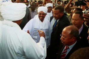 Hundreds of supporters welcome Sudanese President Omar al-Bashir, center, on his arrival from South Africa as he walks through the crowd at the airport in Khartoum, Sudan, Monday, June 15, 2015. Al-Bashir arrived in Khartoum to cheers of supporters after leaving South Africa, where a court had ordered his arrest based on an international warrant for war crimes charges. (AP Photo/Abd Raouf)