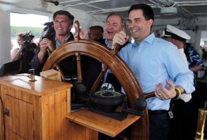 Wisconsin Gov. Scott Walker, right, takes the wheel with former Virginia Gov. Jim Gilmore, center, and former Maryland Gov. Bob Ehrlich during a fundraiser for the Belknap County Republican Committee aboard the motor vessel Mount Washington on Lake Winnipesaukee in New Hampshire, Friday, May 29, 2015. (AP Photo/Charles Krupa)