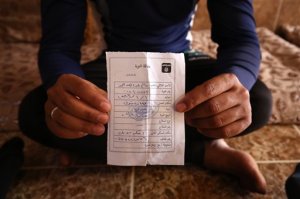 In this Wednesday, May 27, 2015 photo, Salim Ahmed, a former Iraqi Army member, holds the "repentance card" he received from the Islamic State group in June 2014 shortly after the militants took over his home village of Eski Mosul in northern Iraq. The document is part of the apparatus of control the Islamic State group has constructed across its self-declared "caliphate," the territory it conquered in Syria and Iraq. (AP Photo/Bram Janssen)