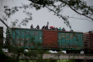 FILE - In this June 20, 2014 file photo, Central American migrants wait atop the freight train they had been traveling north on, as it starts to rain after the train suffered a minor derailment outside Reforma de Pineda, Chiapas state, Mexico. Mexico now deports more Central American migrants than the United States, a dramatic shift since the U.S. asked Mexico for help a year ago with a spike in illegal migration, especially among unaccompanied minors. (AP Photo/Rebecca Blackwell, File)