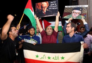Supporters of Tariq Aziz, the only Christian in Saddam Hussein's inner circle, hold the Iraqi flag and portraits of him outside the Arab Medical Center, where his body was brought from Iraq, in Amman, Jordan, early Saturday, June 13, 2015. Aziz died June 5 at age 79. He had been in prison in Iraq since the U.S.-led invasion of Iraq in 2003 and suffered a series of strokes. He faced execution for his role in a government that killed hundreds of thousands of Iraqis. Jordan's government agreed to a request by Aziz's family to bury him in Jordan. (AP Photo/Khaled  Al Odat)