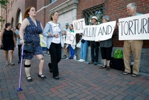 Boston Marathon bombing victim Erika Brannock, foreground left, and her mother Carol Downing, foreground right, walk past demonstrators outside federal court in Boston, Wednesday, June 24, 2015. More than 20 victims of the Boston Marathon bombing and their family members are expected to address the court regarding the attack's impact on their lives before a judge formally sentences bomber Dzhokhar Tsarnaev to death. (AP Photo/Michael Dwyer)