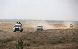 In this Wednesday, June 10, 2015 photo, Palestinian Hamas gunmen ride on the back of a pick-up truck as they patrol the border with Israel near the southern Gaza Strip town of Khan Younis. Nearly a year after a devastating war, Israel and Gaza's Hamas rulers appear to have formed an unspoken alliance in a common battle against the shared threat of jihadis aligned with the Islamic State group. (AP Photo/Khalil Hamra)