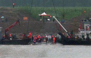 Medical workers, in white, stand as rescuers work on the capsized ship, center, on the Yangtze River in Jianli county of southern Chinas Hubei province, as seen from across the river from Huarong county of southern Chinas Hunan province, Thursday, June 4, 2015. Rescuers cut into the upside-down hull of the river cruise ship and pulled out drowned passengers early Thursday. (AP Photo/Andy Wong)
