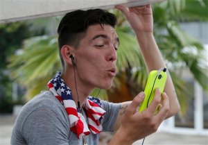 In this March 11, 2015 file photo, Adonis Ortiz chats with his father, who lives in the U.S., using a free Wi-Fi network at a center run by famed artist Kcho, in Havana, Cuba.  Cuba says it's expanding Internet access by adding Wi-Fi capacity to dozens of state-run Internet centers and more than halving the cost that users pay for an hour online. (AP Photo/Desmond Boylan, File)