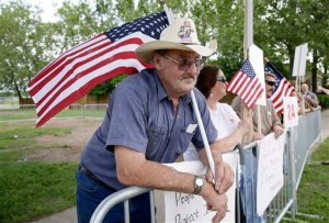 Richard Hoffman, of Grinnell, Iowa , stands in a protestors pen before the arrival of Democratic presidential candidate Hillary Rodham Clinton at a rally, Sunday, June 14, 2015, in Des Moines, Iowa. Seeking an army of volunteers, Clinton is trying to build an organizational edge in Iowa as some of her lesser-known Democratic rivals clamor for attention in the state that tripped up her first presidential campaign. (AP Photo/Charlie Neibergall)