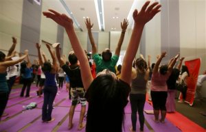 Participants stretch their arms during yoga poses as they join the International Yoga Day inside a mall in suburban Taguig, south of Manila, Philippines on Sunday, June 21, 2015. Yoga enthusiasts bent and twisted their bodies in complex postures across India and much of the world on Sunday to mark the first International Yoga Day. (AP Photo/Aaron Favila)