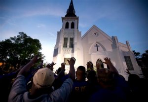 The men of Omega Psi Phi Fraternity Inc. lead a crowd of people in prayer outside the Emanuel AME Church, Friday, June 19, 2015, after a memorial in Charleston, S.C. Thousands gathered at the College of Charleston TD Arena to bring the community together after nine people where shot to death at the church on Wednesday. The current brick Gothic revival edifice, completed in 1891 to replace an earlier building heavily damaged in an earthquake, was a mandatory stop for the likes of Booker T. Washington and the Rev. Martin Luther King Jr. Still, Emanuel was not just a church for the black community. (AP Photo/Stephen B. Morton)
