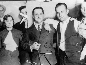 FILE-This is a damaged file photo from Feb. 1934, that is lined with crop marks of John Dillinger, right, posing with the prosecutor of Lake County, Ind., Robert Estill, Sherriff Lillian Holley, left, at the Crown Point, Ind., jail. (AP Photo/File)