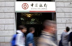 FILE- In this April 15, 2015, file photo, residents walk past the Bank of China branch in downtown Milan, Italy. Italian prosecutors are seeking to indict over 200 people and the Bank of China in connection with a massive money-laundering investigation reported by The Associated Press earlier this month. Prosecutors said more than 4.5 billion euros ($5.1 billion) in proceeds from counterfeiting, prostitution, labor exploitation and tax evasion was sent to China in less than four years using a money-transfer service part-owned by Chinese migrants. (AP Photo/Antonio Calanni, File)