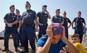 A refugee holds his head in front of a police cordon near the Serbian border in Roszke, Hungary, Friday, Aug. 28, 2015. Hungary deployed police reinforcements to rein in an unrelenting flow of migrants across its porous border Thursday, but refugee activists said the effort appeared futile in a nation whose migrant camps are overloaded and barely delay their journeys west into the heart of the European Union. (AP Photo/Darko Bandic)