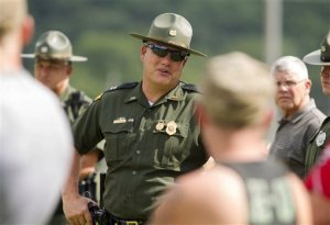 A West Virginia State Police Officer speaks with parents of children from Philip Barbour High School in Philippi, Tuesday, Aug. 25, 2015, after a "hostage-like" situation occurred in the cafeteria of the school. State Police spokesman Lt. Michael Baylous says a suspect was taken into custody Tuesday afternoon at Philip Barbour High School. No injuries were reported. (AP Photo/Ben Queen)