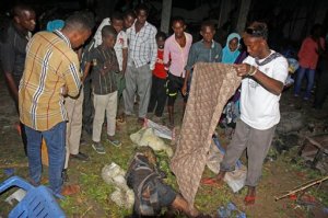 A man covers a dead body in Mogadishu, Somalia, Saturday, Aug. 22, 2015. Four people were killed when a parked car exploded near a bus station in northern Mogadishu, said Capt. Mohamed Hussein. The attack in the capital bore the hallmarks of al-Shabab. (AP Photo/Farah Abdi Warsameh)