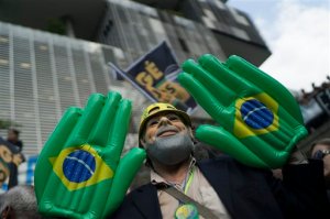 In this Monday, Aug. 24, 2015 photo, a man wearing a mask with the likeness of the former Brazilian president Luiz Inacio Lula da Silva poses for pictures during a protest against layoffs, in front of the Petrobras headquarters in Rio de Janeiro, Brazil. Dozens of federal deputies, senators and other top political figures are under investigation, along with some CEOs of Brazil's top construction and engineering firms who are already jailed for a corroption kickback scheme involving roughly $2 billion in bribes paid by companies in return for grossly inflated building contracts over more than a decade. (AP Photo/Leo Correa)