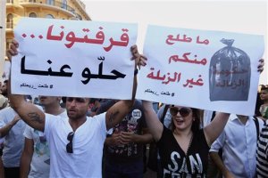 FILE - In this Saturday, Aug. 8, 2015 file photo, Lebanese protesters hold up signs against the Lebanese government during a demonstration against the ongoing trash crisis, at the Martyrs square in downtown Beirut, Lebanon. Starting out as a small group of tech-savvy young activists who organized to protest the garbage that for weeks has been piling up on Beiruts streets, Lebanon's "You Stink" movement has now grown into a popular uprising that seeks to nip at the power base of an entire political class.  Sign at left reads in Arabic 'we're sick of you go away' and at right 'Nothing comes from you but garbage'. (AP Photo/Bilal Hussein, File)