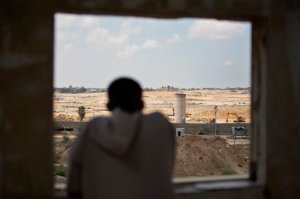 In this Sunday, Aug. 30, 2015 photo, a Palestinian man looks from a window at bulldozers and diggers work at the Egyptian side of the border with Gaza Strip. Egyptian military bulldozers have been digging through the sand along the border in recent days, pressing ahead with what appears to be a renewed campaign to pressure Gazas Hamas rulers and stamp out militant activity along the border.(AP Photo/Khalil Hamra)