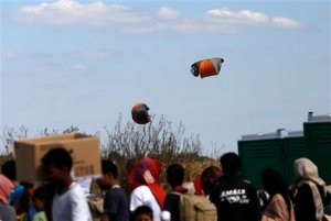 Migrant tents are caught in the wind and fly into the air over makeshift migrant camp in Roszke, southern Hungary, Wednesday, Sept. 9, 2015. Leaders of the United Nations refugee agency warned Tuesday that Hungary faces a bigger wave of migrants in the next few days and will need international help to provide aid and shelter on its border.(AP Photo/Darko Vojinovic)