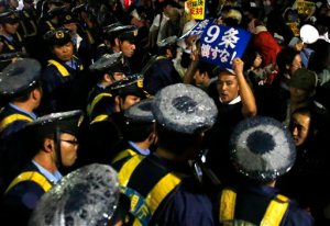In this Friday, Sept. 18, 2015 file photo, a protester shouts slogans as he is surrounded by police officers during a rally against the Japanese government in front of the parliament building in Tokyo. Japan's parliament is moving toward final approval of legislation that would loosen post-World War II constraints placed on its military, an issue that has sparked sizeable street protests and raised fundamental questions about whether the nation needs to shift away from its pacifist ways to face growing security challenges. (AP Photo/Shuji Kajiyama, File)
